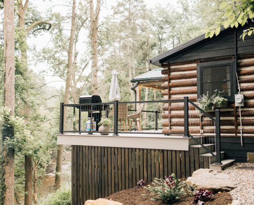 Rustic cable with composite deck with aluminum vertical cable railing overlooking wooded area and stream