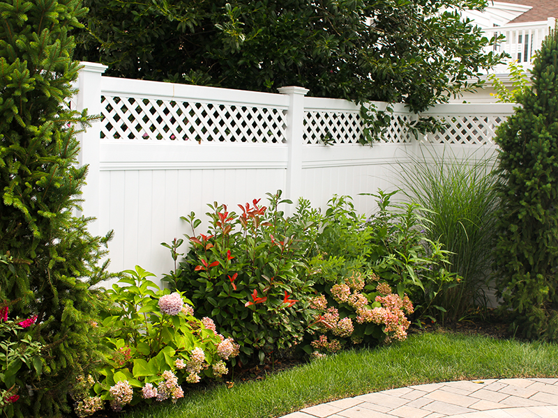 vinyl privacy fence with lattice and flowering landscape